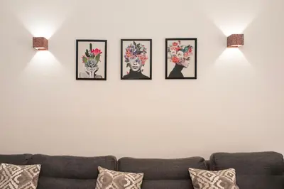 four framed pictures on a white wall with a couch at Esperidon Luxury Apartment Glyfada in Athens