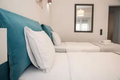 a bedroom with two beds and a couch with pillows at Esperidon Luxury Apartment Glyfada in Athens