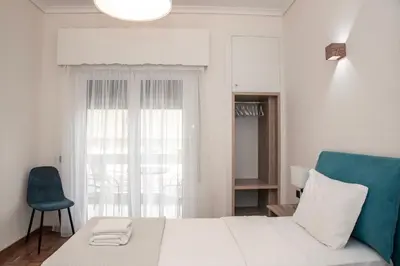 a bedroom with a white bed and a blue chair at Esperidon Luxury Apartment Glyfada in Athens