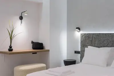 a bedroom with a white bed and a chair at Loom Suite Downtown Athens in Athens