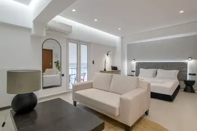 a bedroom with a bed and a couch and a chair at Loom Suite Downtown Athens in Athens