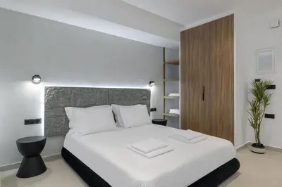 a bedroom with a white bed and a wooden cabinet at Loom Suite Downtown Athens in Athens