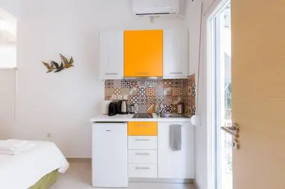 a small kitchen with white cabinets and an orange at Cosy studio in the Petralona neighbourhood in Athens