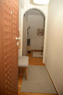 a hallway with a chair and an open door at Hara's Apartment in Athens