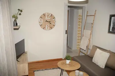 a living room with a couch and a clock on the wall at Hara's Apartment in Athens