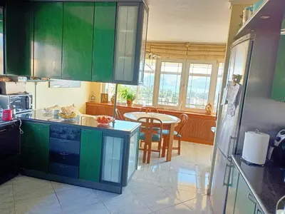 a kitchen with green cabinets and a table in it at Τάνια in Anavissos