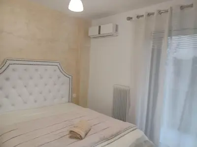 a bed with a white headboard and a window at Cozy Renovated Apartment in Athens