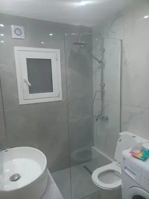a white bathroom with a shower and a toilet at Cozy Renovated Apartment in Athens