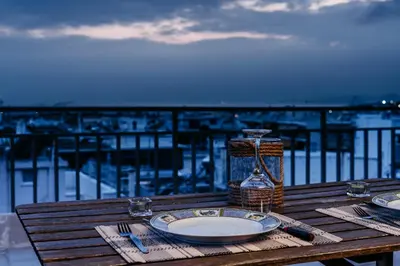 a wooden table with a plate of food and a view of the ocean at Penthouse of diamond in Athens