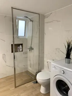 a bathroom with a shower and a toilet and a washing machine at The Temple of Comfort in Athens