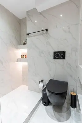 a bathroom with a black toilet and marble walls at Acropolis Luxurious Legacy in Athens