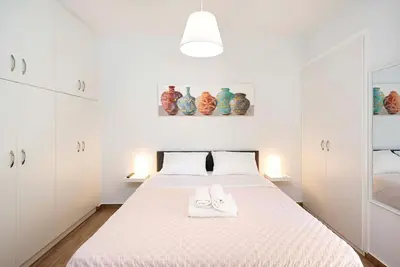 a white bedroom with a bed with two towels on it at Filoxenia MG Projects city center in Athens