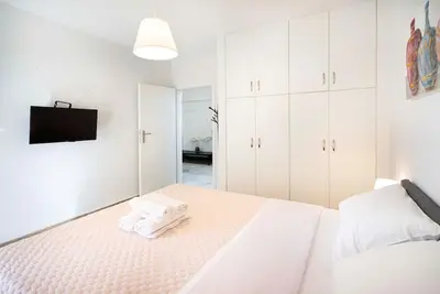 a white bedroom with white cabinets and a bed at Filoxenia MG Projects city center in Athens