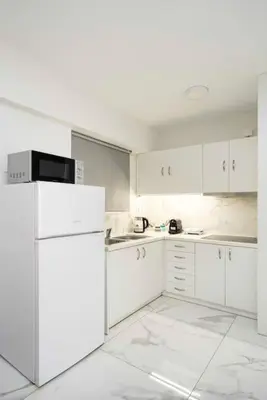a kitchen with white cabinets and a white refrigerator at Filoxenia MG Projects city center in Athens
