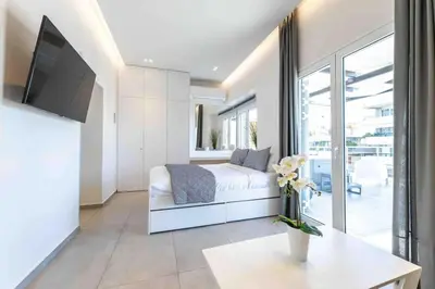 a white bedroom with a bed and a tv at Jacuzzi Luxpenthouse PFaliro in Athens