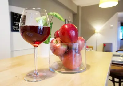 a glass of wine and a vase of apples on a table at Live in Athens, PSYRRI Meet Me Here Apartments in Athens