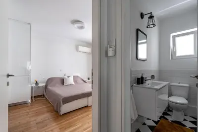 a white bathroom with a bed and a toilet and a sink at The Black Marble - Sea View, 2BR, 2BA in Paleo Faliro in Athens