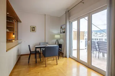 a room with a table and chairs and a balcony at City view roof top apt 10min from Acropolis museum in Athens