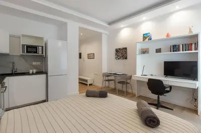 a living room with a kitchen and a desk with a television at Brand new apartment in Athens in Athens