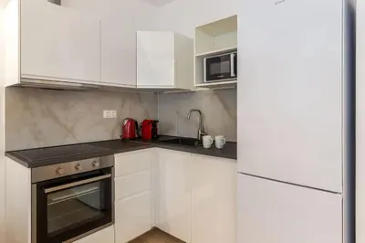 a small kitchen with white cabinets and a refrigerator at Brand new apartment in Athens in Athens