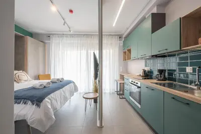 a bedroom with a bed and a kitchen with blue cabinets at Stylish Urban Suites in Athens
