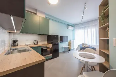 a kitchen with green cabinets and a table and a dining room at Stylish Urban Suites in Athens