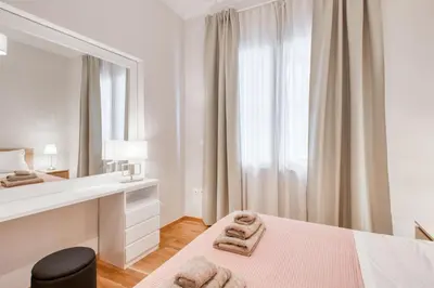 a white bedroom with a bed and a mirror at Modern 2-bedroom apt, 200m from the Acropolis in Athens
