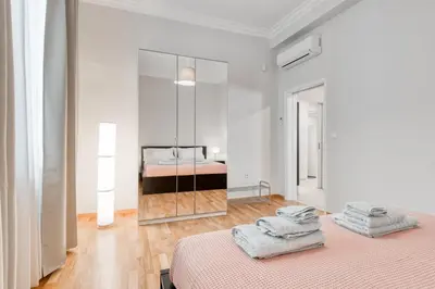 a white bedroom with two beds and a mirror at Modern 2-bedroom apt, 200m from the Acropolis in Athens