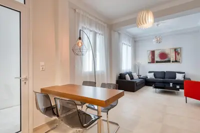 a living room with a wooden table and chairs at Modern 2-bedroom apt, 200m from the Acropolis in Athens