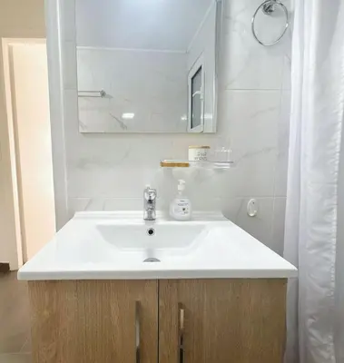 a bathroom with a white sink and a mirror at Sunny two-bedroom apartment next to Panathenaic Stadium in Athens