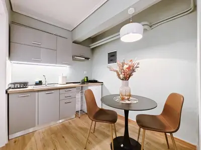 a kitchen with a table with chairs and a vase with flowers at 5min Metro, Sotiria, Iatriko, Semi-Basement in Athens