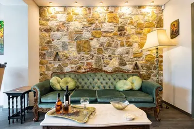 a living room with a green couch and a stone wall at Queen's stone legend, royal living by Acropolis in Athens