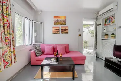 a living room with a pink couch and a table at Canto-Home Alongside The Acropolis in Athens