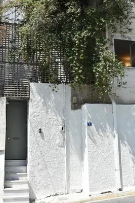 a white wall with two doors next to a building at Canto-Home Alongside The Acropolis in Athens