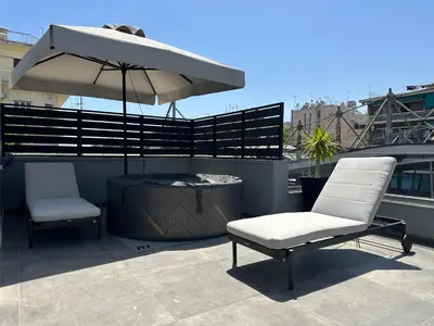 two chairs and an umbrella on top of a roof at T&T Luxury Apartments - Rooftop Jacuzzi in Athens