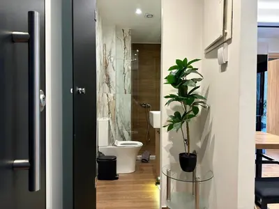a bathroom with a toilet and a plant in the doorway at T&T Luxury Apartments - Rooftop Jacuzzi in Athens