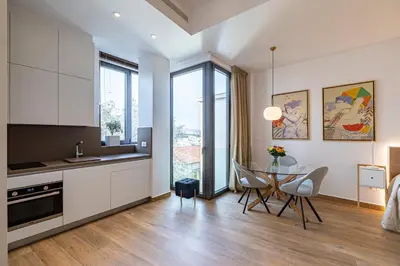 a kitchen with white cabinets and a table with chairs at ART-W Executive Apartments in Athens