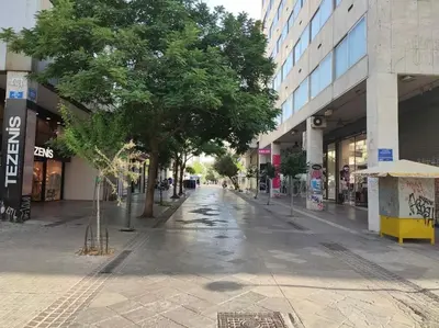 an empty street in a city with trees and buildings at Ancient Agora Hideaway in Athens