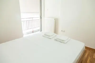 a white bed in a room with a large window at Cozy - Bright & New apart. - Downtown in Athens