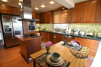 a kitchen with wooden cabinets and a table with chairs at Grand Villa Nefeli - Pool & Jacuzzi in Lagonissi