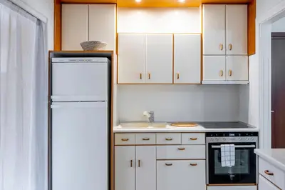 a kitchen with white cabinets and a refrigerator at IVY Charm Acropolis View 2BR Apartment Neos Kosmos in Athens