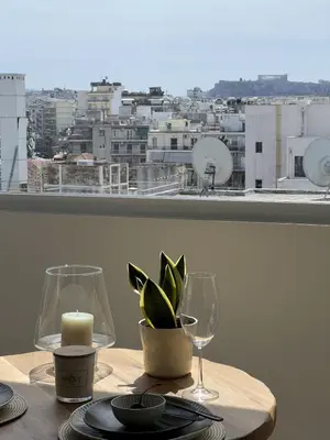 a table with a candle and two glasses and a plant at Dafnis View in Athens
