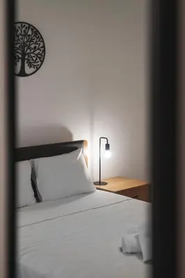 a bedroom with a white bed with a tree picture on the wall at Oculus 2BD Athens Central Escape by Live&Travel in Athens