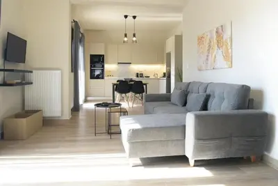 a living room with a gray couch and a kitchen at Aellō luxury apartments in Markopoulo