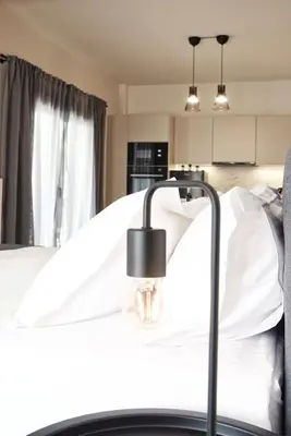 a bed with white sheets and a lamp on it at Aellō luxury apartments in Markopoulo