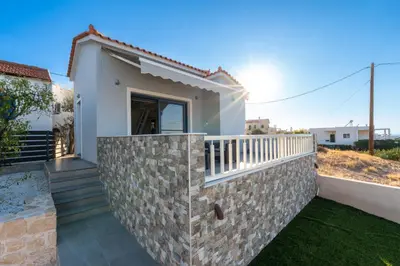 a small white house with a stone wall at Nikoli House in Vaia