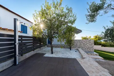 a house with a fence and a tree on a walkway at Nikoli House in Vaia