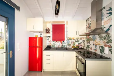 a kitchen with a red refrigerator and white cabinets at Nikoli House in Vaia