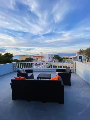 a patio with couches and tables on a balcony at Nikoli House in Vaia