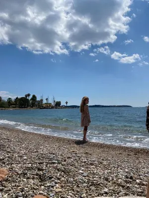 a young girl standing on a beach near the water at Athens-Riviera apartment in front the sea Voula in Athens